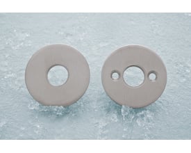 Assa Abloy roset 2501-2238 til træskrue c38 mm, vist som to runde, sølvfarvede dele med forskellige hulmønstre.