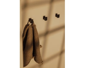 Metallbude Palo vægknage i sort, vist med en brun vaffelvævet håndklæde hængende på den.