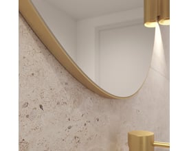 Nærbillede af kanten på Loevschall Refine spejlet med børstet messingramme og en tekstureret væg.