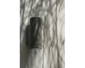 Astro 7586 Dartmouth Twin udendørs væglampe i sort, monteret på en lysgrå væg med skygger fra træer.