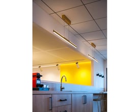 SLV ONE LINEAR 100 pendel i messing monteret i et moderne køkkenmiljø over en køkkenø.