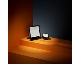 Sort LEDVANCE Floodlight Area Asym LED-projektør på orange podie, vist sammen med en mindre projektør.