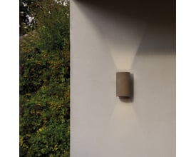 Astro Lighting Dunbar 160 LED væglampe i støbt beton monteret på en lys væg med en frodig grøn busk til venstre.