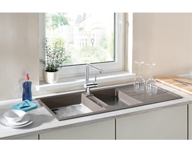 Blanco Linus-S-F køkkenarmatur i krom med udtrækstud monteret på et brunt dobbeltsidet vaskebord ved et vindue.