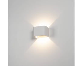 SLV MANA lampeskærm i hvid gips tændt på en hvid væg, som udsender lys opad og nedad.