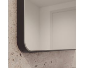 Nærbillede af hjørnet af Loevschall Refine spejlet med en tynd, sort metalramme og afrundede kanter.