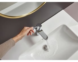Hansgrohe Waterforms L håndvaskarmatur i krom, vist med en kvindes hånd der betjener et-grebet, mens vand løber i vasken.