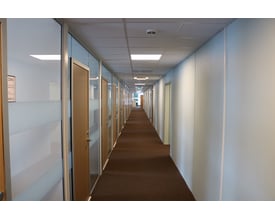 SG Armaturen Sense Pro Connect LED panel monteret i et kontor loft med en lang gang og døråbninger.