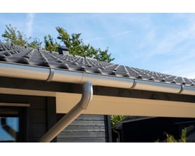 Plastmo aluzink 90° indvendig udvendig rendejern på et mørkt hus med tegltag.