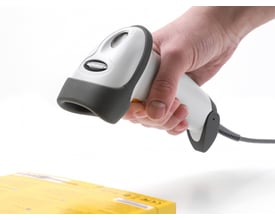 DeLock USB 1D barcodescanner i hvid og grå holdes over en gul æske med stregkode.