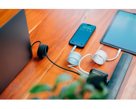 Verbatim Sync & Charge USB-C-kabel i blå ligger oprullet på et træbord ved siden af en telefon og tablet.
