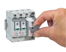 Legrand transientbeskyttelse type 2, 3P+N, med 40kA Imax og plug-in moduler, vist med en hånd der betjener en grå kontakt.