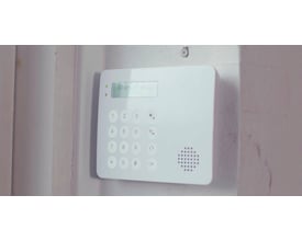 TrueGuard tastatur med LCD display, monteret på en rå væg, viser "Alarm frakoblet" på skærmen.