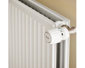 Nærbillede af Stelrad Hygiene radiator med hvid termostatknop og synlige paneler i en let gylden baggrund.