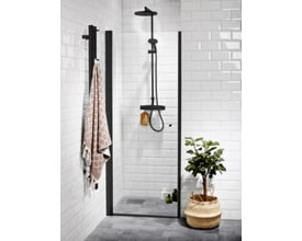 Moderne brusekabine med Vetro svingdør med sort profil og klart glas, monteret på hvidt flisegulv og væg.