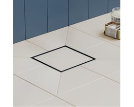 Hansgrohe afløbsskål i børstet rustfrit stål med en ramme på 100 x 100 mm, monteret i et cremefarvet flisegulv med mørkeblå vægpaneler bagved.