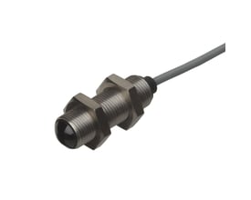 Carlo Gavazzi fotoaftaster M12 med gevindhus, mørk optisk front og gråt kabel; sender kode 1 med 20 m rækkevidde.