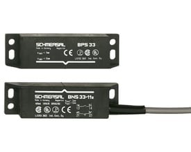 Schmersal BNS 33-11z magnetaftastere i sort kunststof hus, et med kabel og synlige mærkningsdetaljer på hvid baggrund.