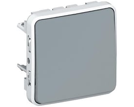 Legrand Plexo 55 afbryder i grå, vist fra en let skrå vinkel, med tydelige monteringsdetaljer og hvid ramme.