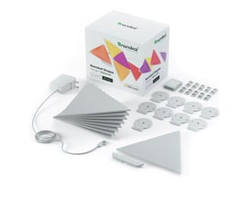 Nanoleaf Shapes Triangles sat op på en mørkegrøn væg i et spiseområde med et unikt og farverigt lysmønster.
