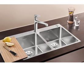 BLANCO ANDANO 340/340-IF/A MXI køkkenvask med tilbehør som skærebræt, kniv og citron, viser vaskens funktionelle design.