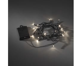 Konstsmide lyskæde med 40 varm hvide LED og sort ledning, rullet sammen ved siden af batterikassen på mørk baggrund.