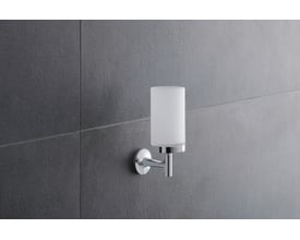 Duravit Starck T glasholder i krom med matteret glas monteret på en grå flisevæg, set skråt forfra.