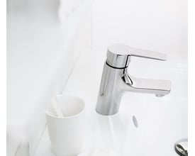 Mora Cera B5 håndvaskarmatur i krom monteret på en hvid porcelænsvask, ved siden af en hvid holder med tandbørster.