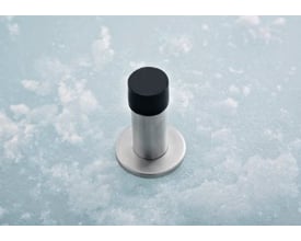 Assa Abloy vægdørstop på 85 mm med rund fod, børstet stål og sort gummianslag.