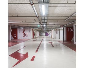 THORNeco JULIE polyesterarmaturer monteret i en lang parkeringskælder med betonloft og tydelige markeringer på gulvet.