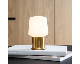 Komplet SACKit Base London lampe i messing finish, monteret på en bordplade med bøger som dekoration.