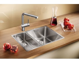 Blanco Andano 340/180-IF/N UXI køkkenvask i rustfrit stål med to kummer og en moderne armatur på en træbordplade.