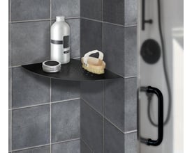 Smedbo Sideline hjørnehylde til indmuring i mat sort, 200x200 mm, med shampooflaske, creme og børste. Ses i et badeværelseshjørne med grå klinker.