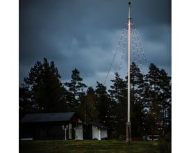 Konstsmide flagstangskæde monteret på flagstang ved skumringstid, skaber stemningsfuld belysning med 100 LED-lys.
