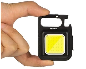 Ironside Micro genopladelig håndlampe med sort hus, gul lysflade og karabinhage holdes mellem fingrene.