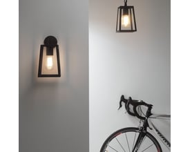 Astro 7105 Calvi vægarmatur installeret på hvid væg ved siden af en cykel, viser lampens alsidighed og stil.