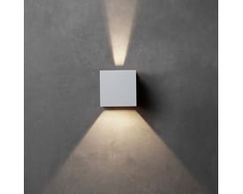 Hvid Lumenlight Toscana væglampe med up- og downlight monteret på en grå væg.