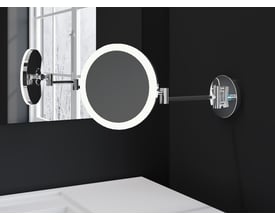 Cosmic vægmonteret makeupspejl med LED-lys i mat sort, med 5x forstørrelse og justerbar lysfarve, monteret på sort væg ved siden af et vindue.