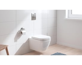 Grohe Solido Euro Ceramic hængetoilet i hvid med toiletsæde, monteret på en flisevæg ved siden af et vindue.