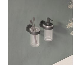 Cosmic tandkrus i mat sort, vist ved siden af en sæbedispenser på en grå væg med planter.