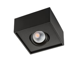 Nærbillede af et sort SG Armaturen Cube Lux loftspot med indbygget LED-lys og reflekterende linse, sat i relief på en matsort ramme.