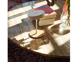 Halo Design On the move batteri bordlampe i hvid metal placeret på et marmorbord med bøger ved siden af. Den har en rund lampehoved og en elegant stander.