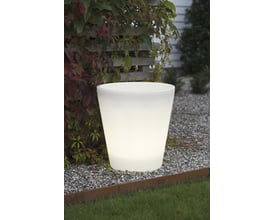 Stor hvid Konstsmide Assisi LED blomsterkrukke tændt udendørs om dagen på grus og græs.