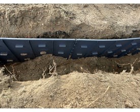 GreenMax TRG45 rodguidepanel i sort plast installeret i jorden for at styre planterødder på en 450 x 600 mm overflade.