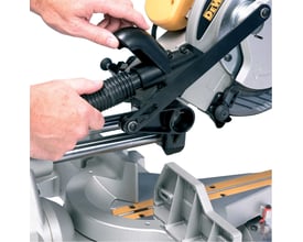 Dewalt DW712N-QS geringssav med udtræk, hvor brugeren justerer savhovedet med støvudsugning monteret.