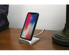 Scosche Qi Dock/Powerbank med opladet iPhone, vist fra siden på et træbord i et hjemmemiljø.