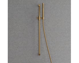 Detaljeret visning af Scandtap brusesætets stick-formede håndbruser og 1500 mm slange i børstet messing, monteret på en betonlignende baggrund.
