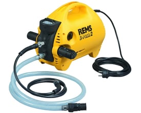Rems E-Push 2 elektrisk trykprøvepumpe i gul plast med sort håndtag, trykmåler og tilslutningsslanger på hvid baggrund.