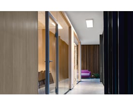 SG Armaturen Sense Surface Connect panel monteret i et moderne kontormiljø med glasvægge og træbeklædning.