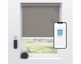 Gråt MotionBlinds-mørklægningsrullegardin monteret i et vindue med appstyring og trådløse signaler.